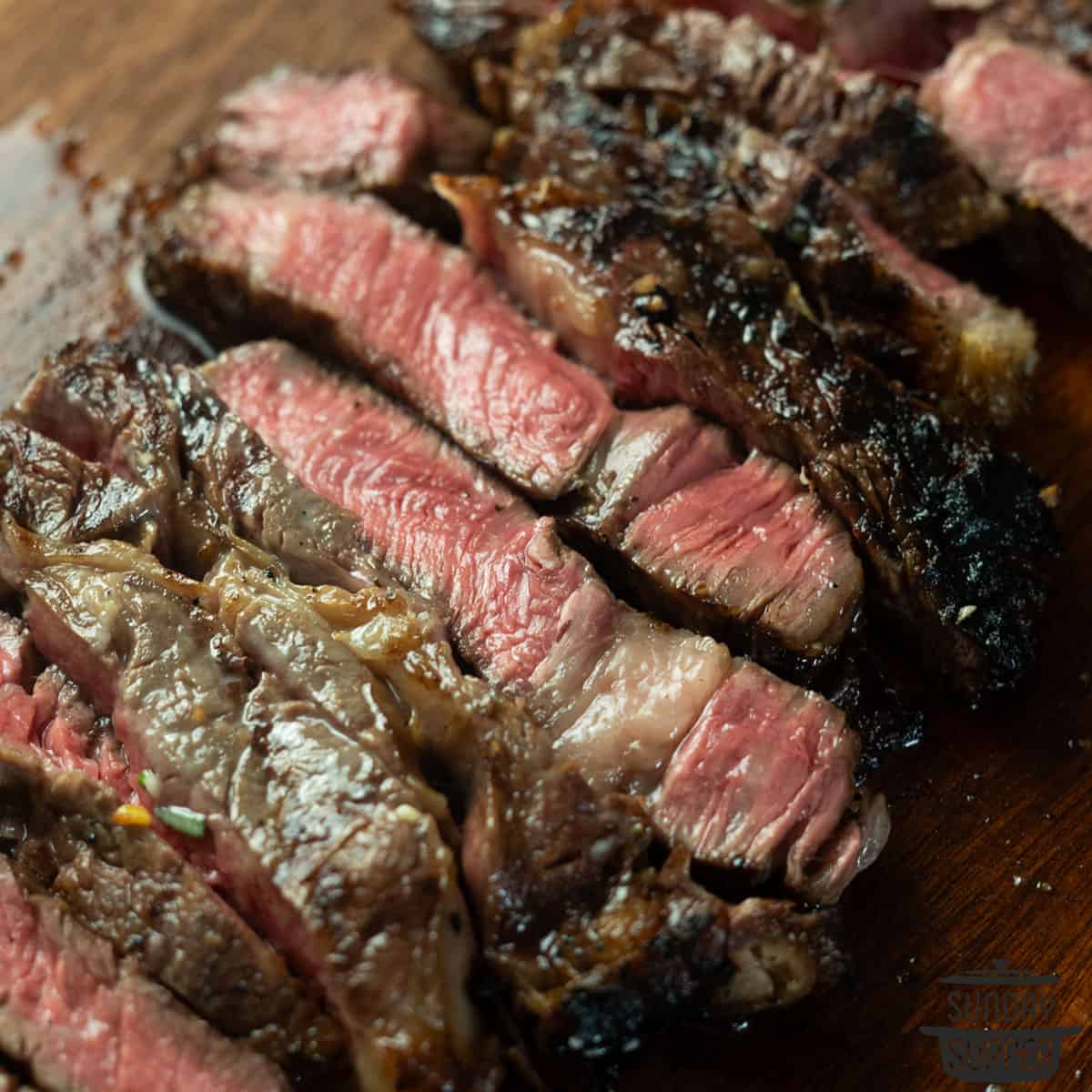 sliced grilled chuck steak on a wood cutting board