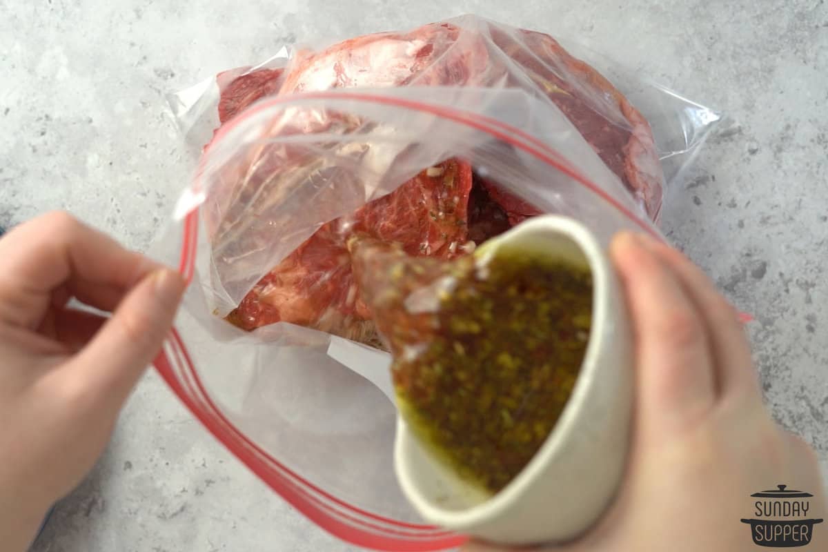 adding marinade to steaks in a bag