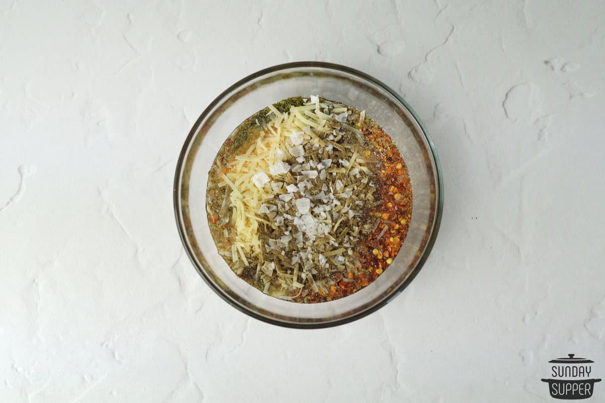 adding pizza oil dipping sauce ingredients into a bowl