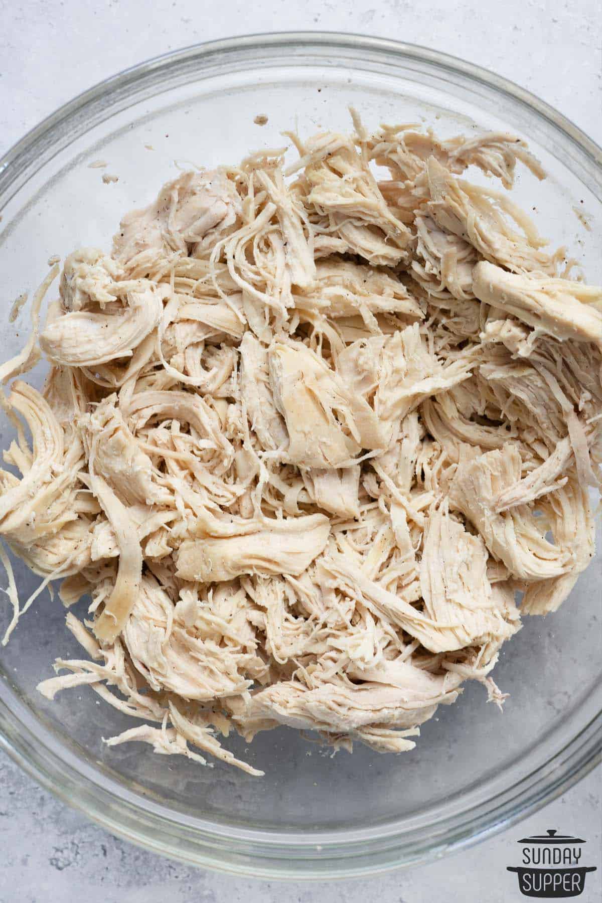 overhead view of shredded chicken in a clear bowl