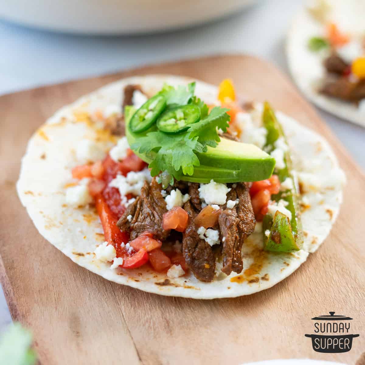 close up of steak fajitas in a warm tortilla with toppings