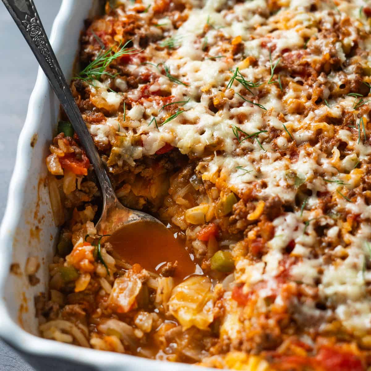 cabbage casserole up close in a baking dish with a portion missing and a spoon