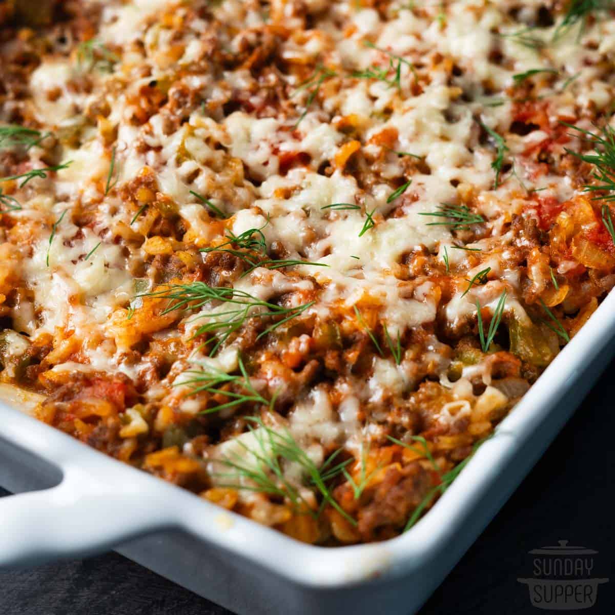 close up of baking dish with stuffed cabbage casserole, topped with herbs