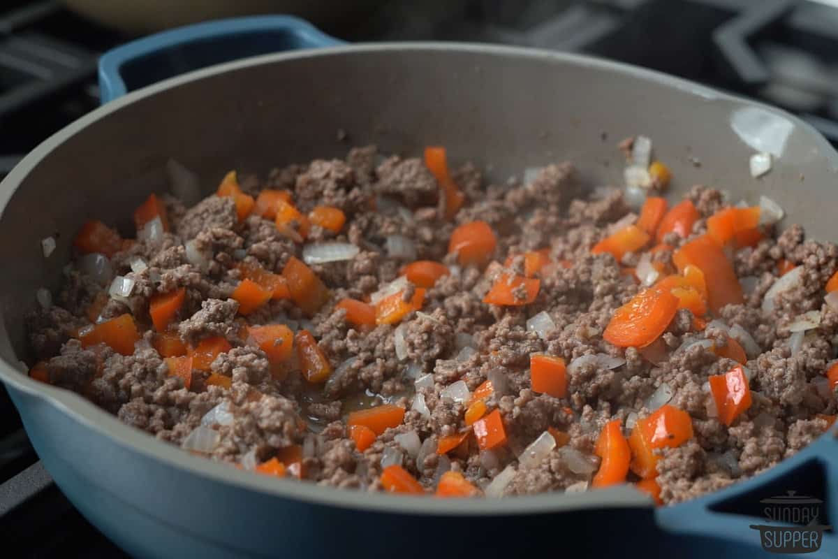 adding onions and peppers to ground beef