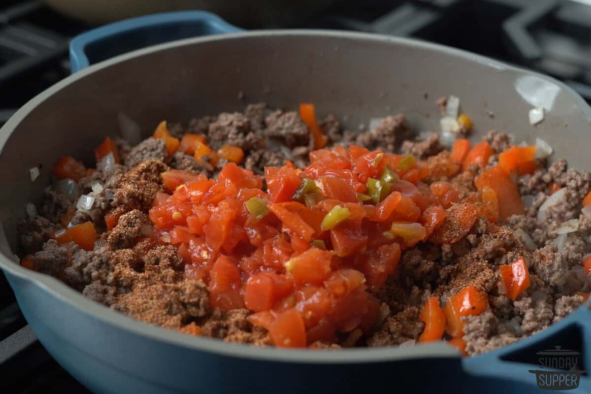 seasoning and adding tomatoes to ground beef