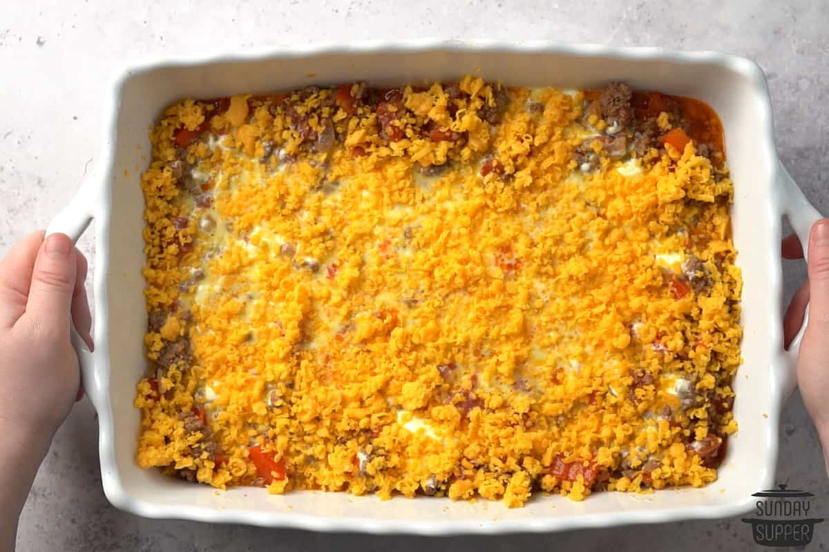 adding shredded cheese to a casserole dish