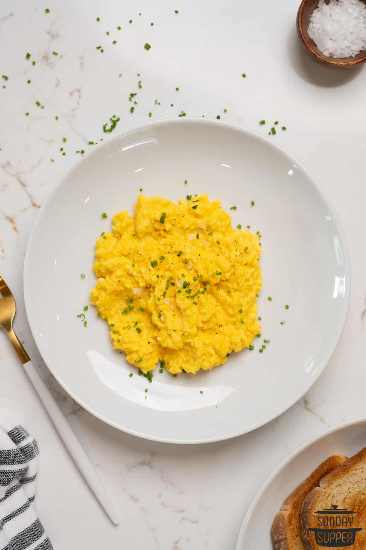 fluffy scrambled eggs on a plate with chives