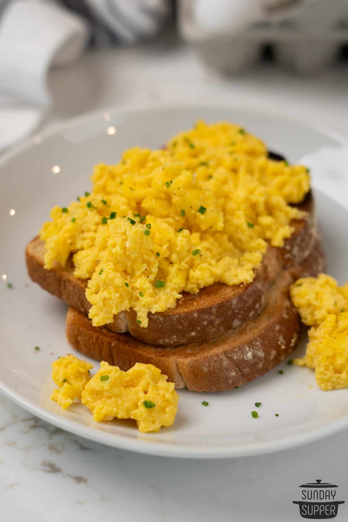 two slices of toast with scrambled eggs on top