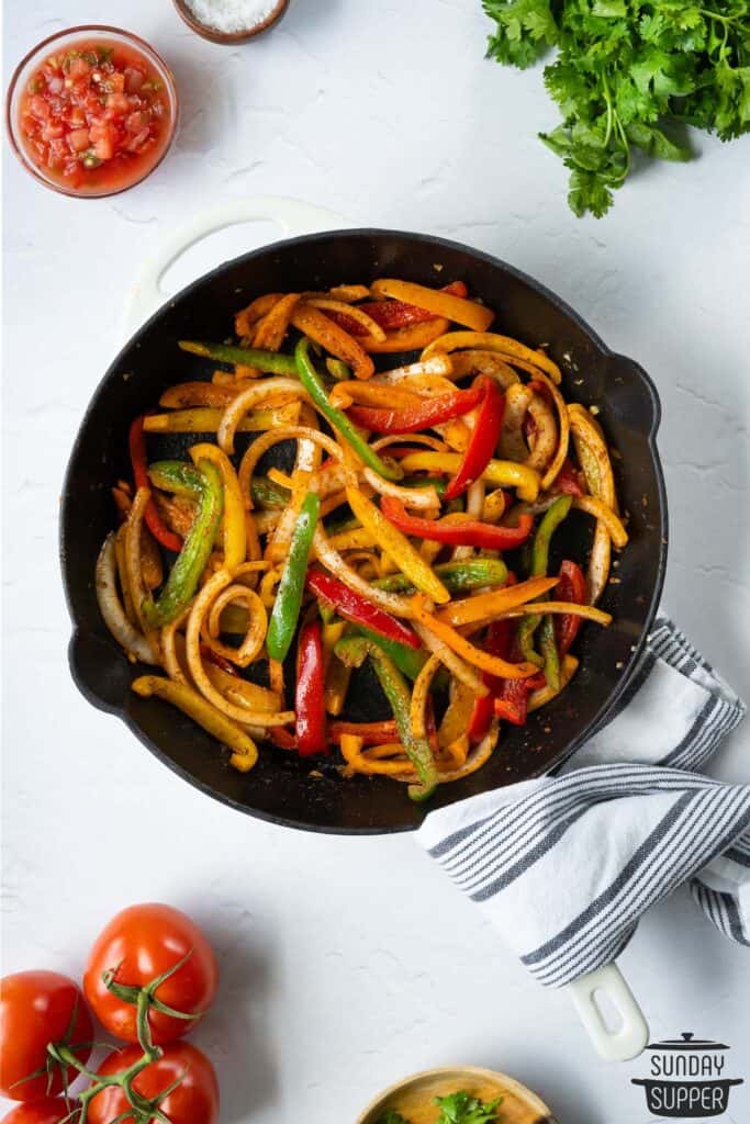 a pan of fajita veggies with salsa and tomatoes