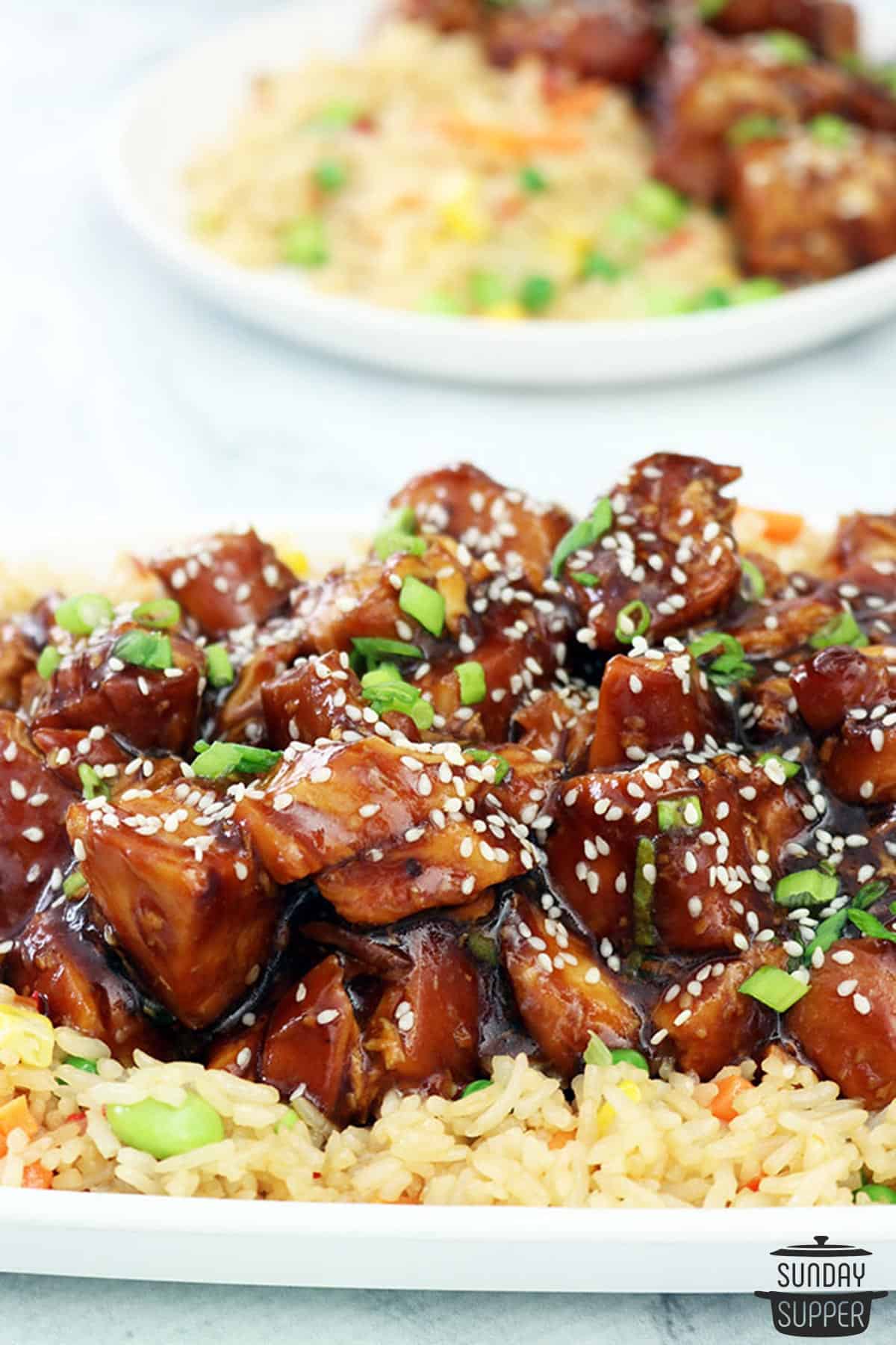 honey sesame chicken on a plate of fried rice
