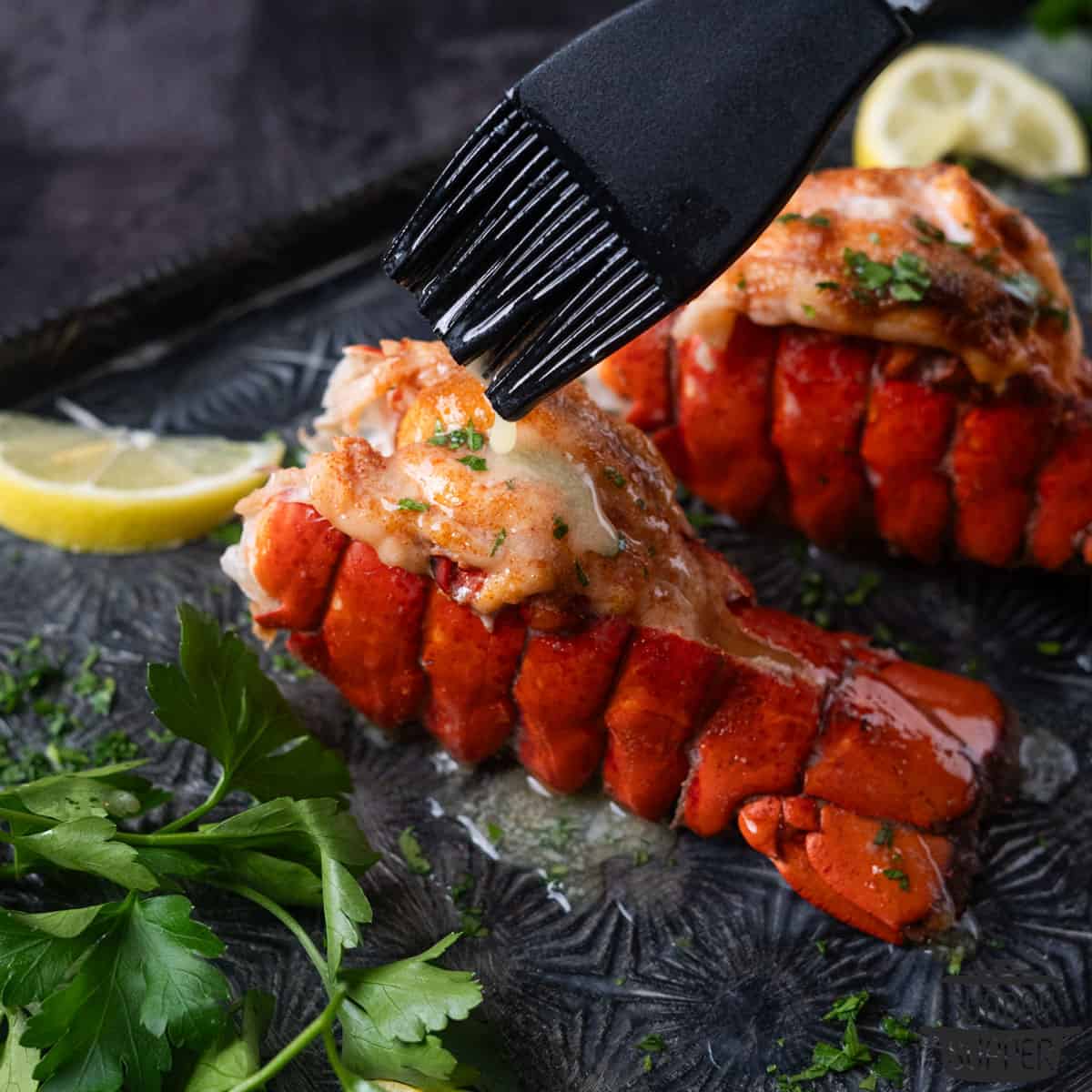 extra butter being brushed on lobster tails