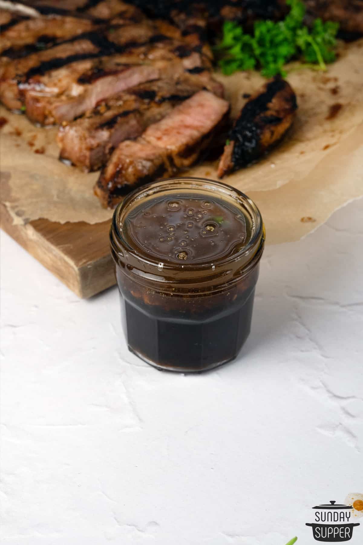 a jar of pork marinade next to a cutting board with pork steaks