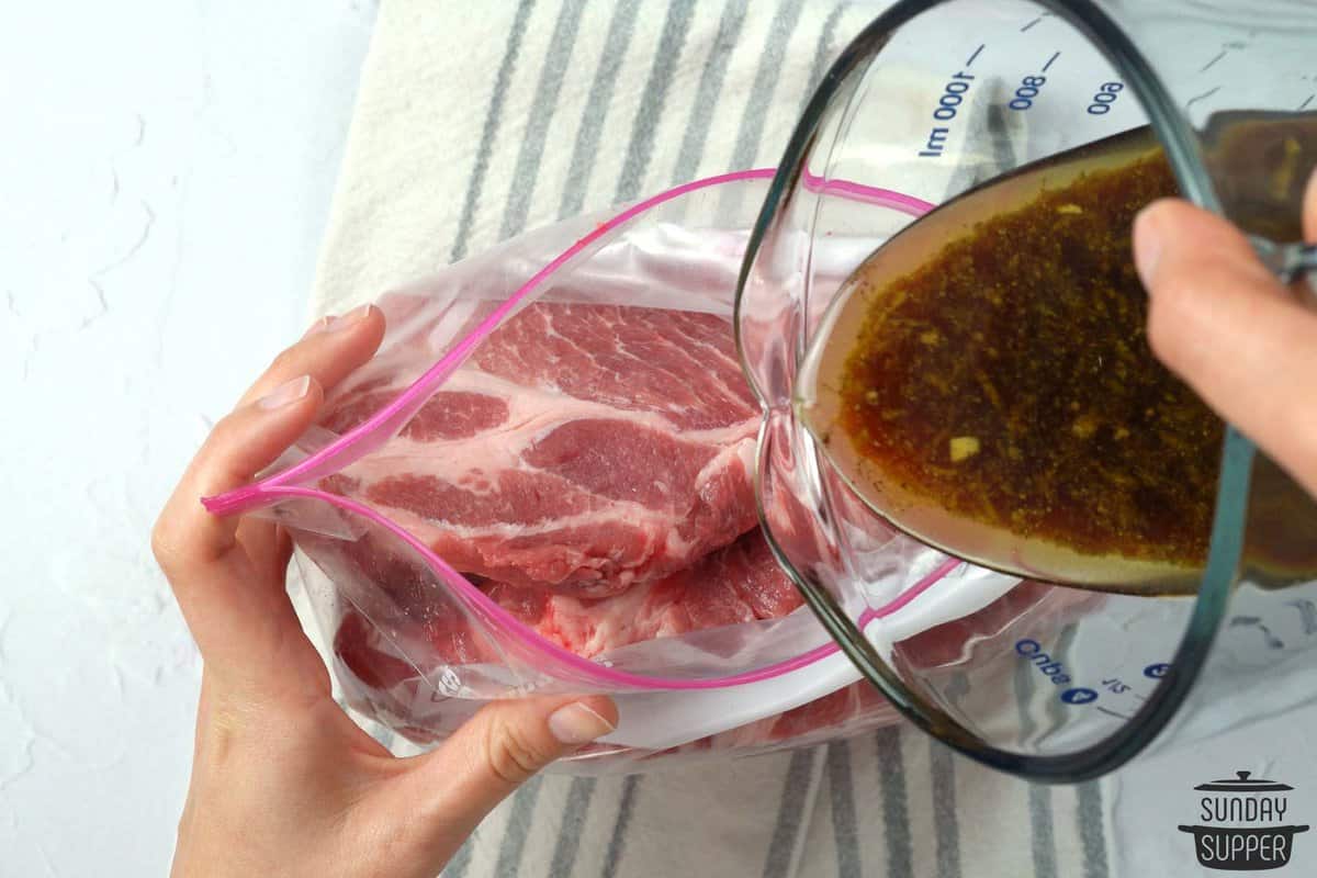 marinade being poured on pork steaks in a ziplock bag