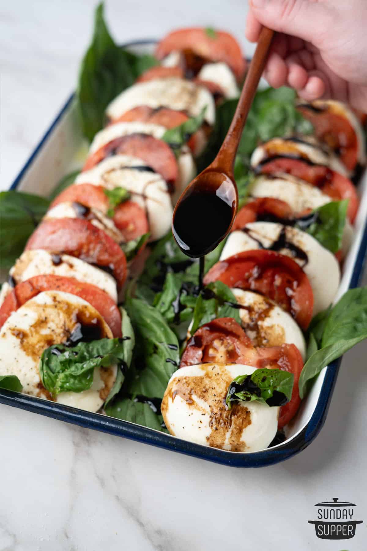 balsamic glaze being drizzled over a fresh tomato and mozzarella salad
