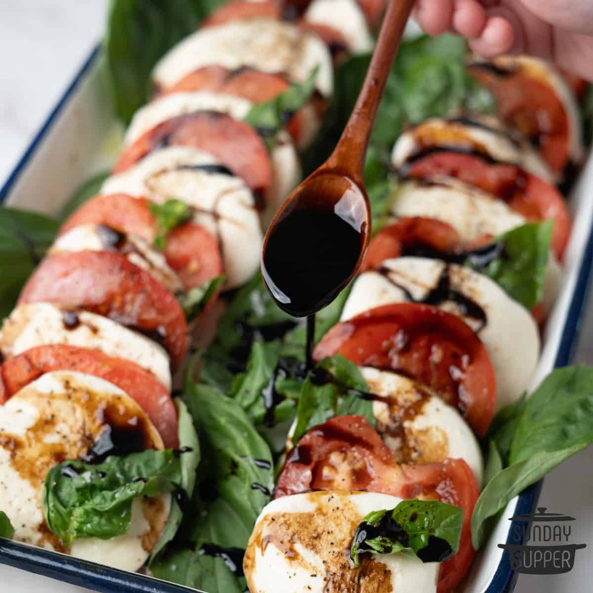 balsamic glaze being drizzled over a caprese salad
