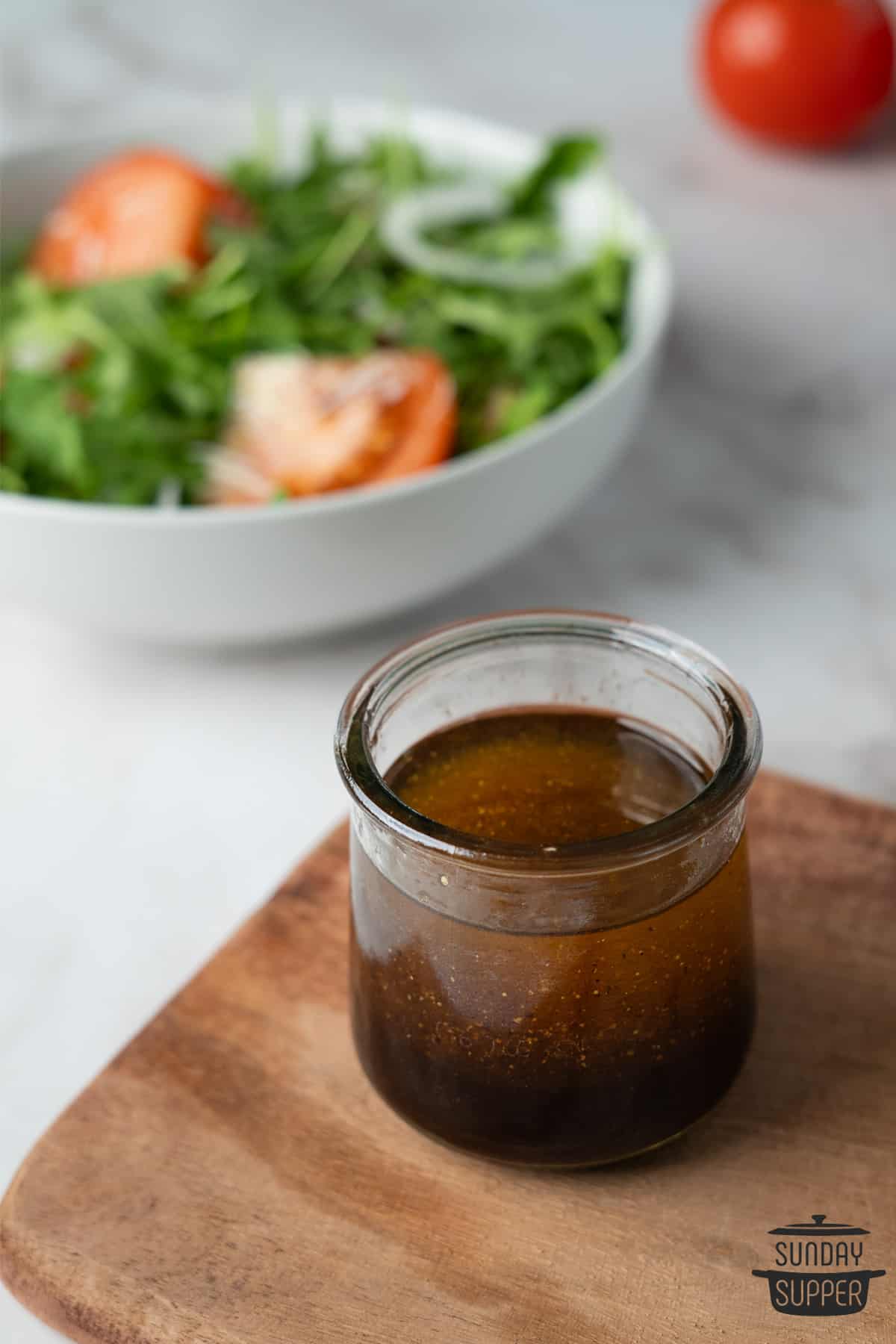 balsamic vinaigrette in an open jar next to a bowl of salad