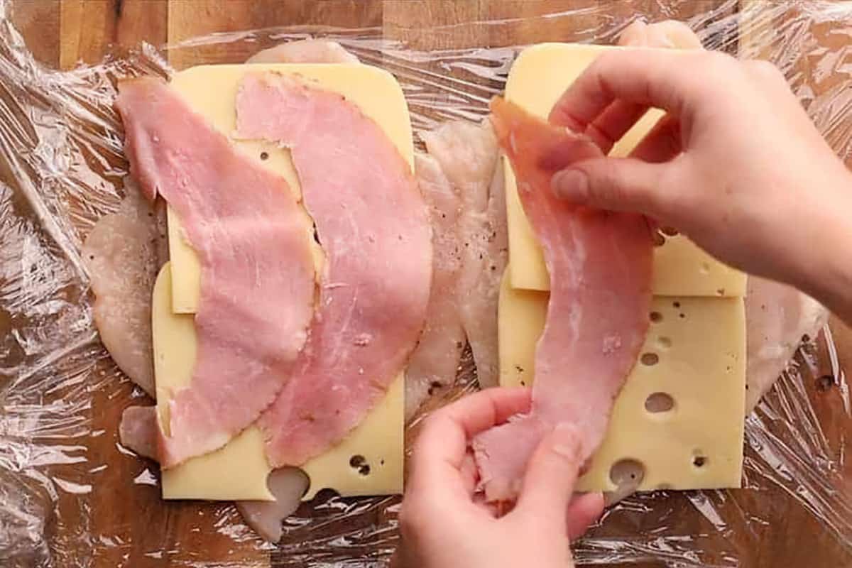 layering cheese and ham on chicken breast