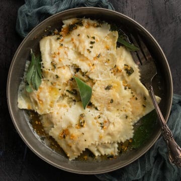 lobster ravioli in a bowl with a fork and fresh herbs on top