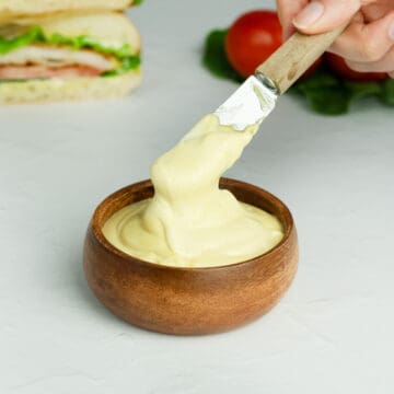 close up of mayo mustard sauce in a wood bowl with a knife inside