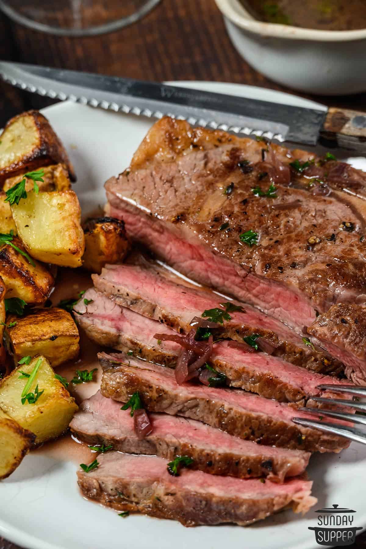 a dinner plate with sliced steak and potatoes