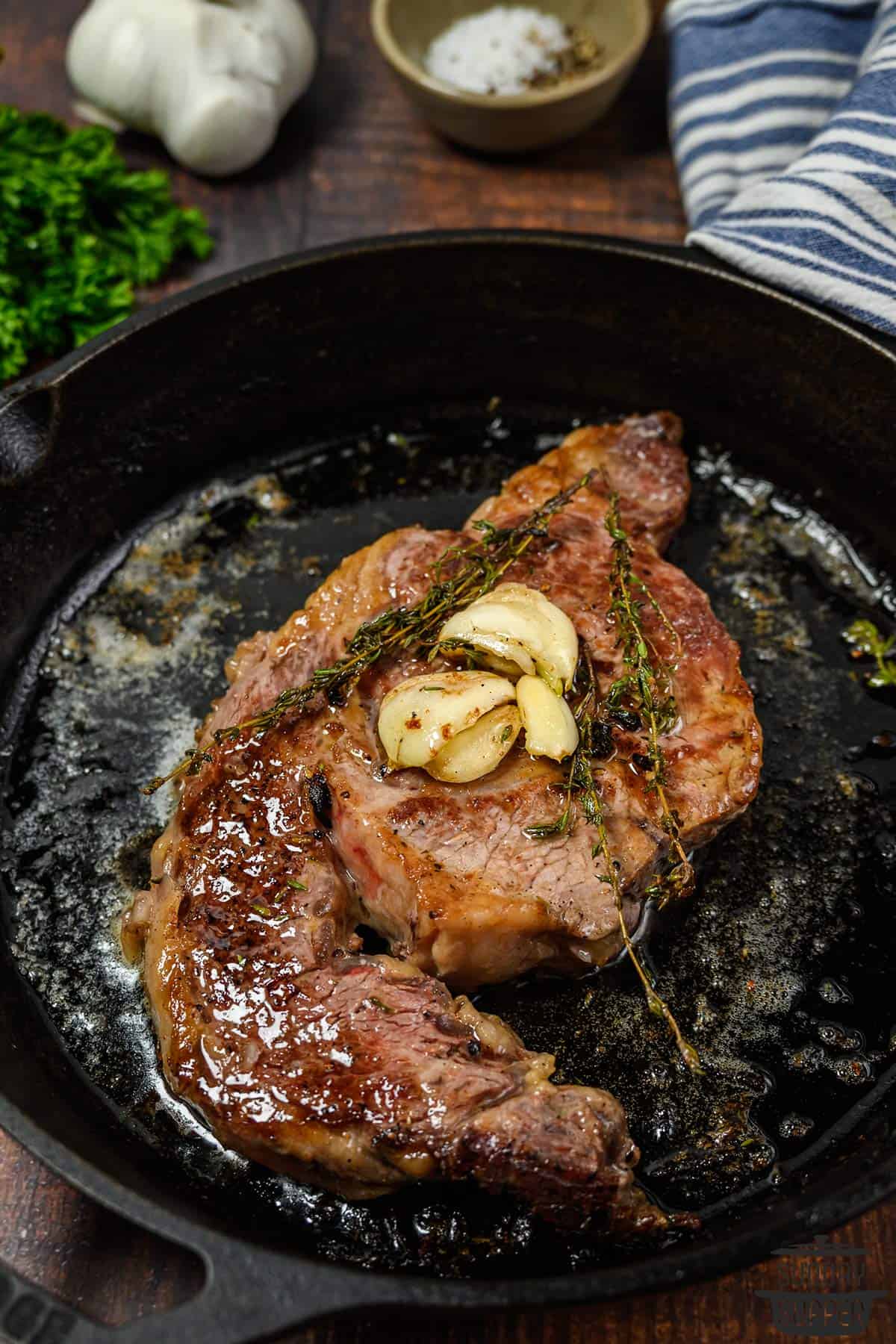 seared steak with extra garlic and thyme in a cast iron pan