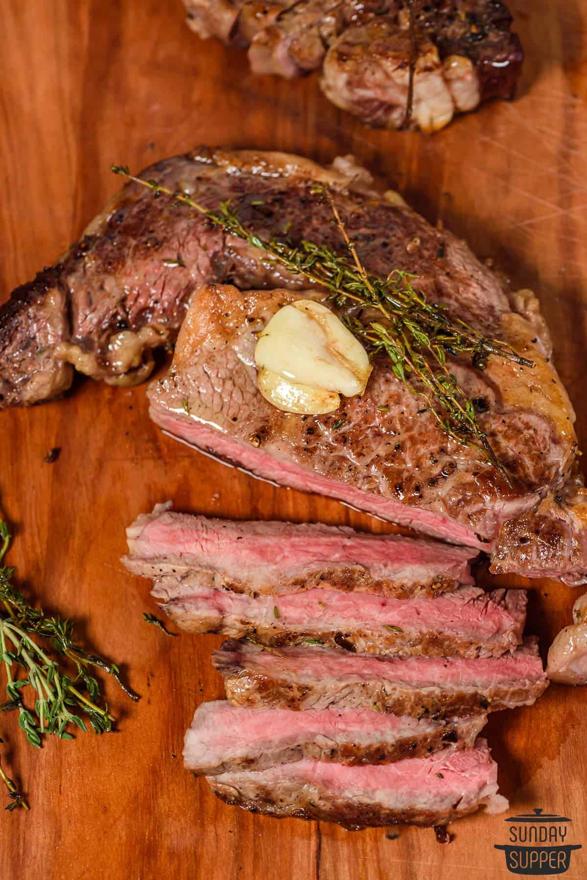a seared steak on a cutting board sliced with garlic