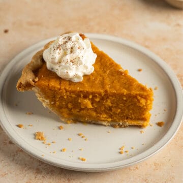 a slice of sweet potato pie in a plate with whipped cream