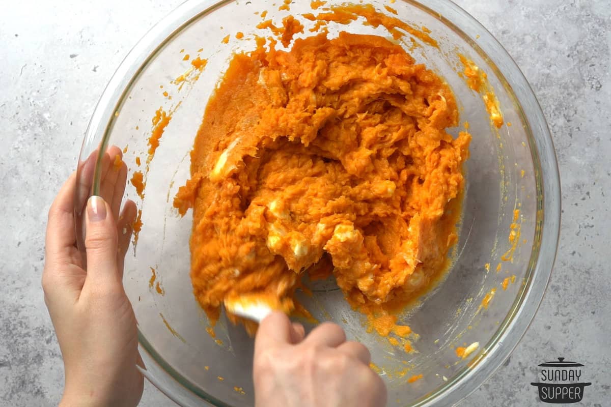 the sweet potato flesh and butter being mixed in a bowl