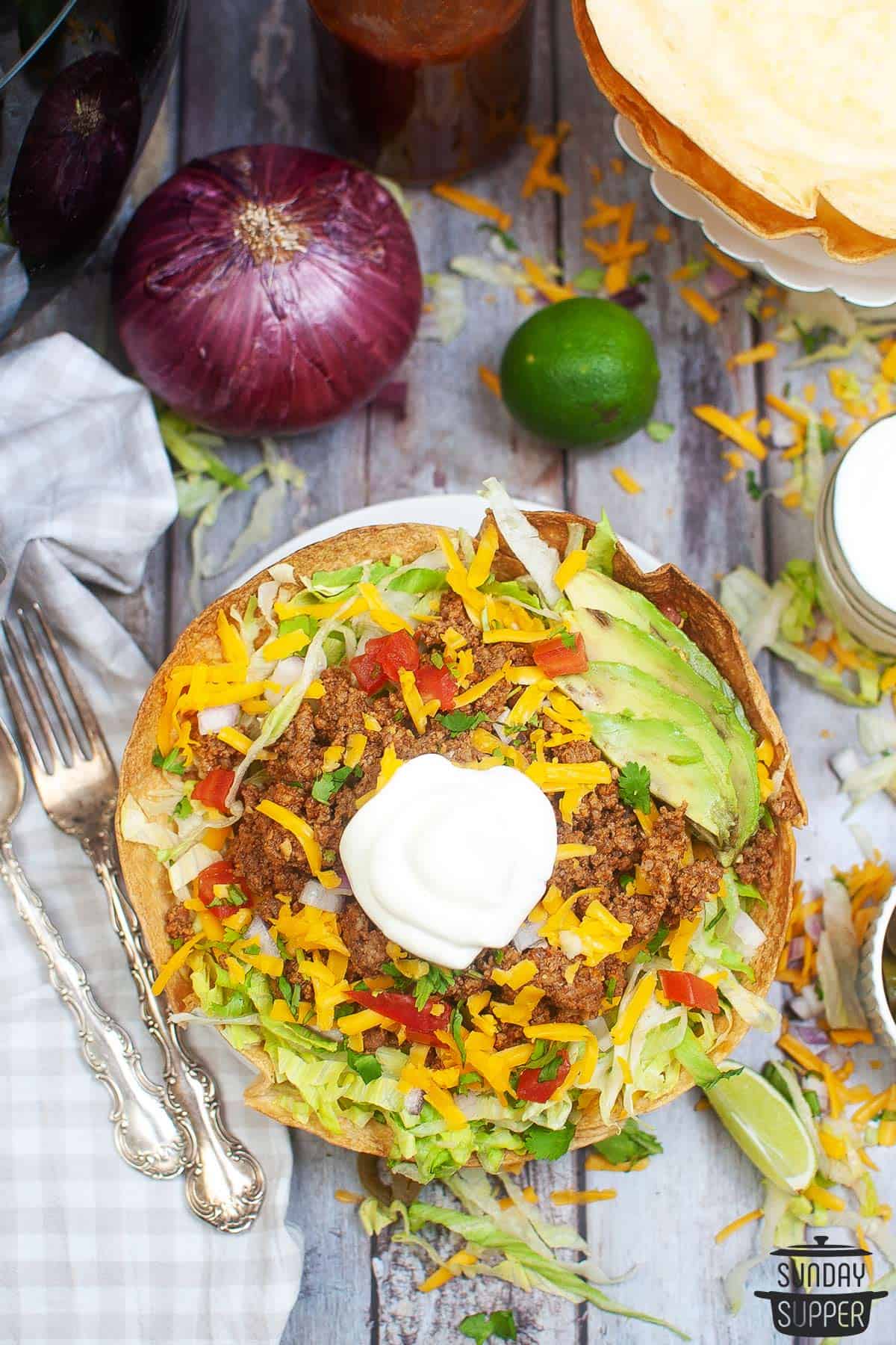 a taco bowl with salad next to extra toppings
