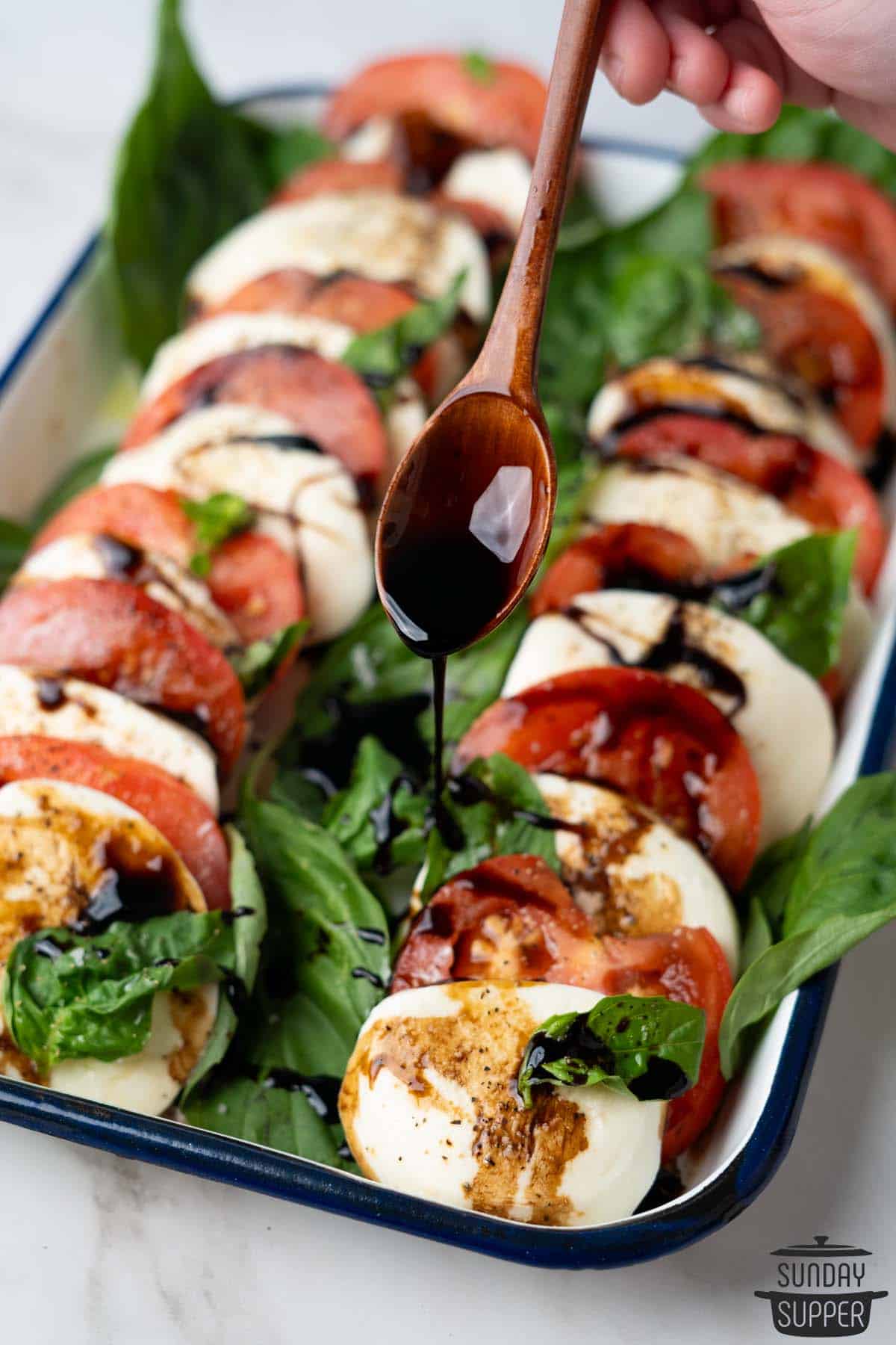 more glaze being drizzled over caprese salad