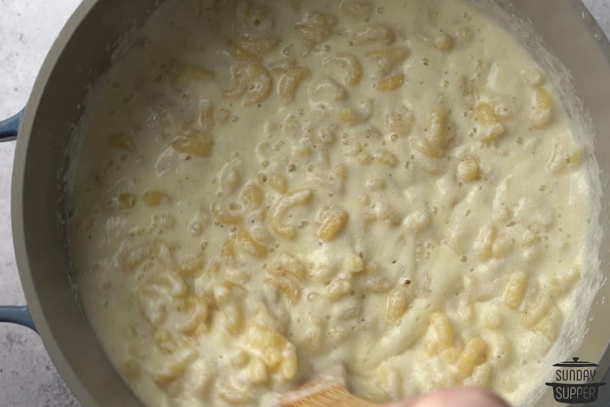 mixing cheese sauce with cooked noodles