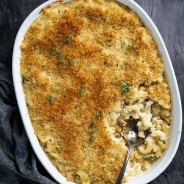 close up of truffle macaroni and cheese in a white casserole dish with a spoonful inside