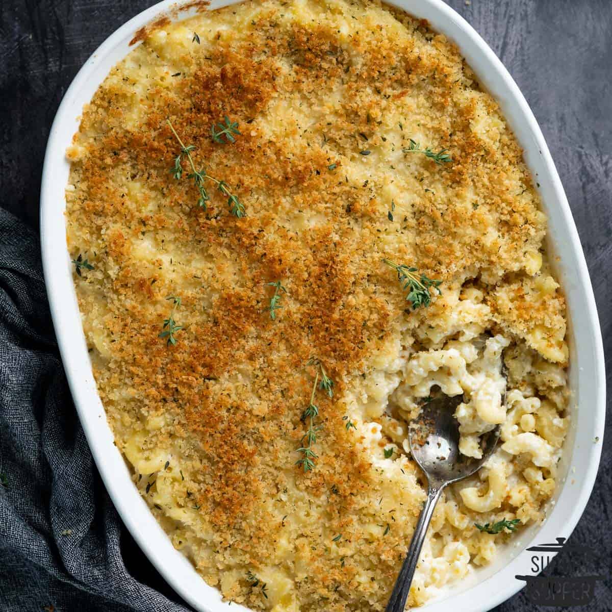 close up of truffle macaroni and cheese in a white casserole dish with a spoon