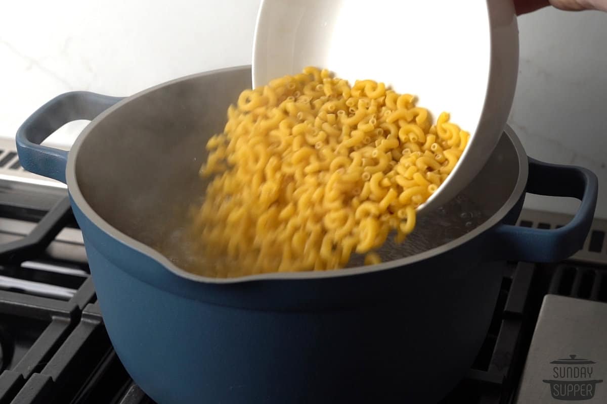 adding macaroni to a boiling pot of water