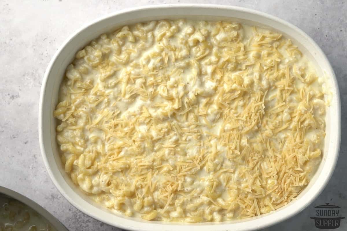 adding half of the truffle macaroni and cheese to a white casserole dish