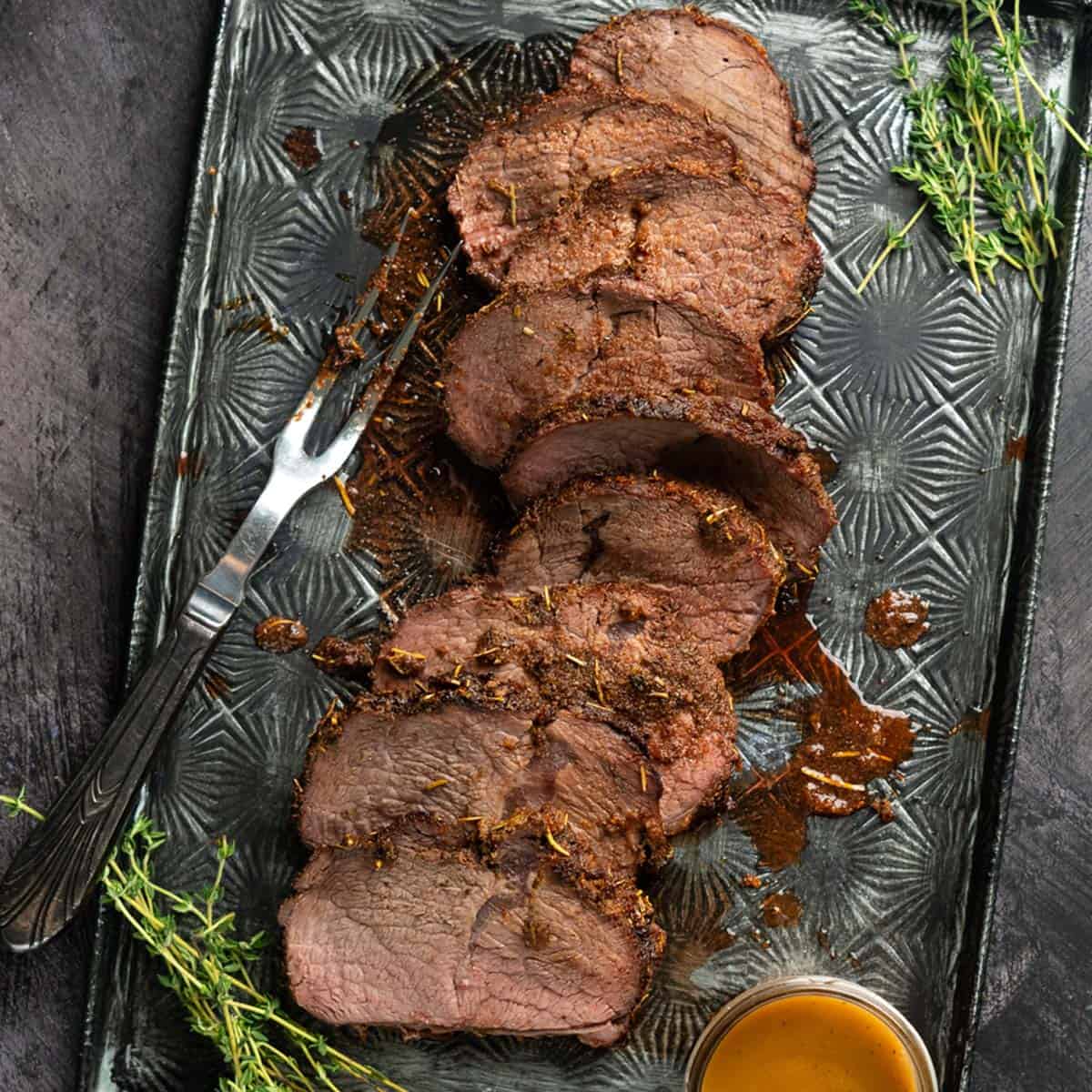 sliced chuck roast on a serving plate with juices