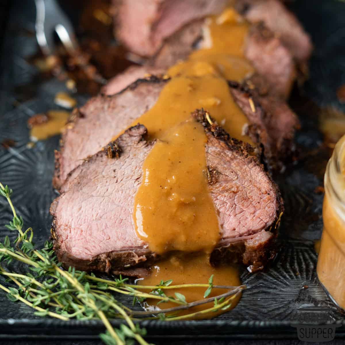 sliced chuck roast on a serving plate with gravy