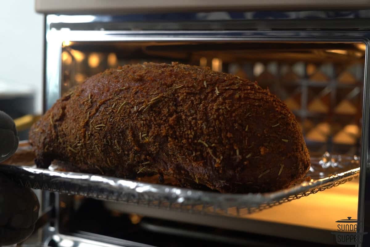 the seasoned chuck roast being placed in the air fryer