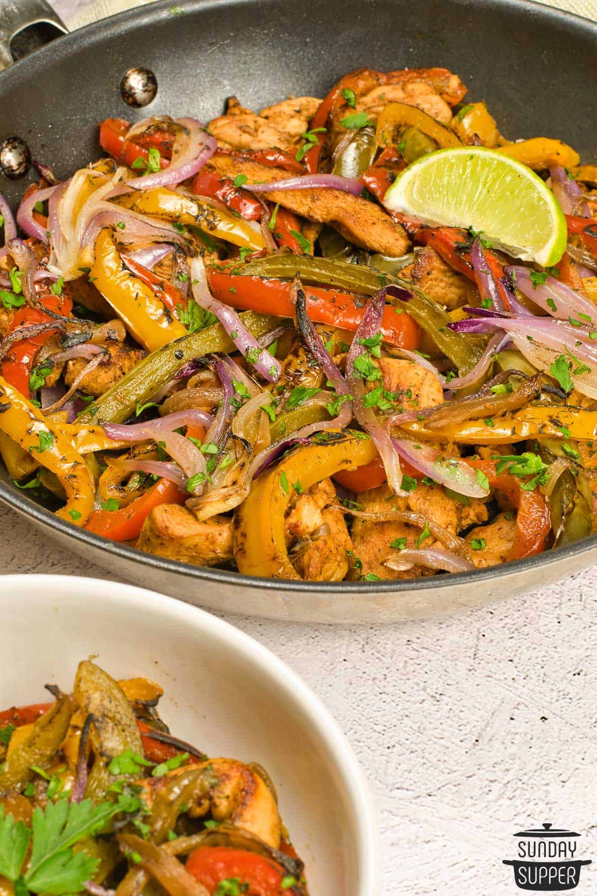 a pan of marinated chicken fajitas with peppers, onions, and lime