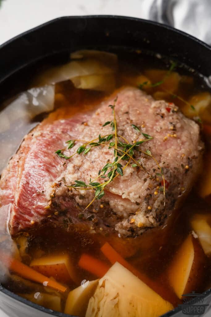 a pot of broth, vegetables, and corned beef