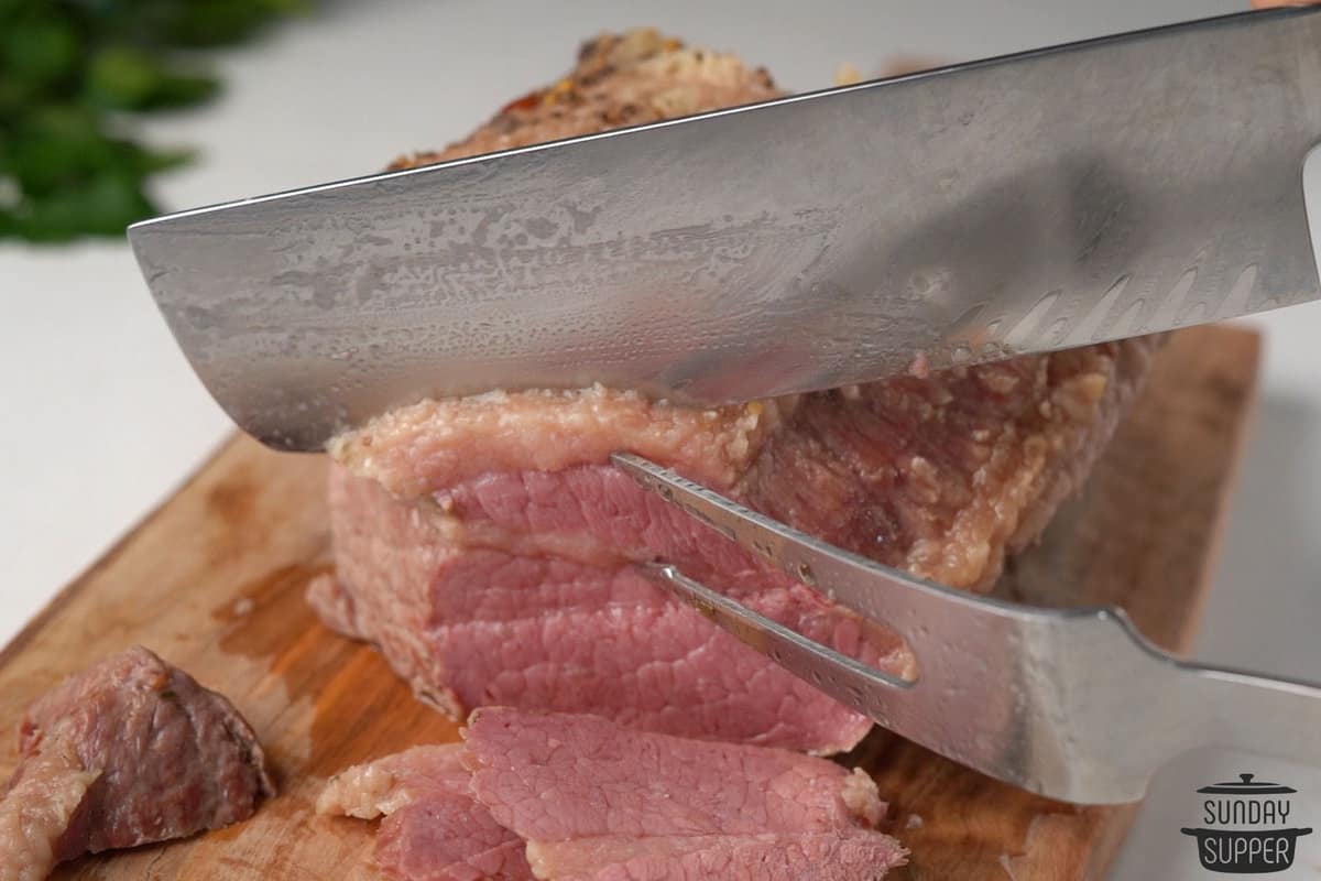 the corned beef being sliced on a cutting board