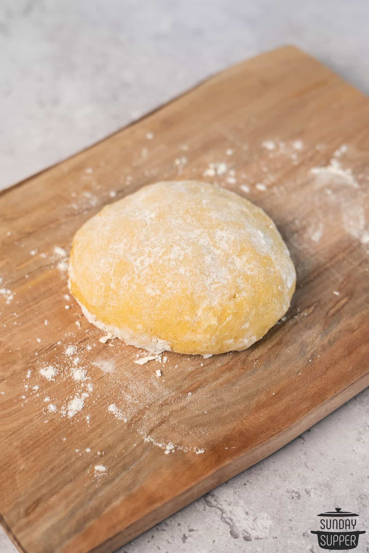 a ball of pasta dough on a floured cutting board