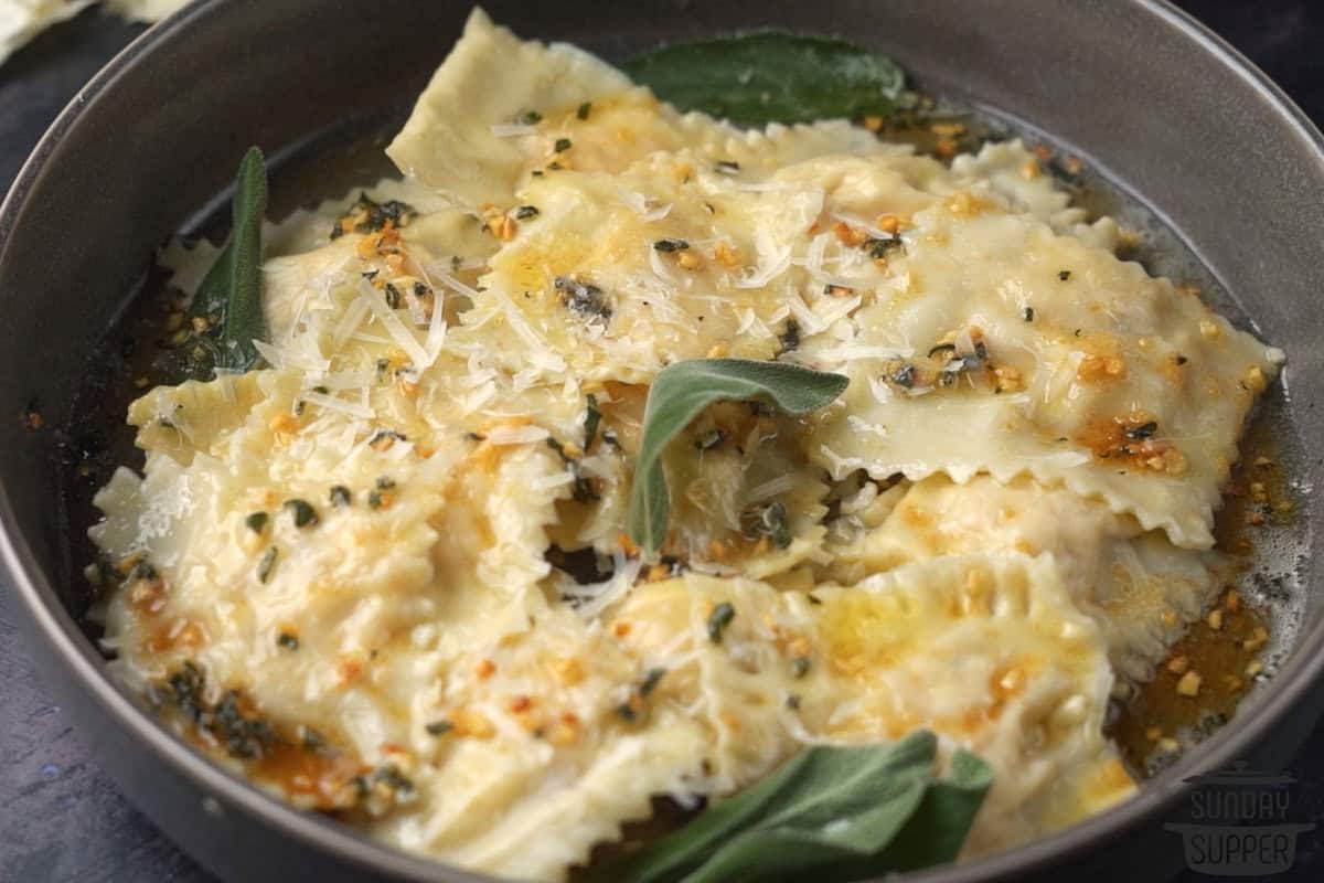 a bowl of homemade ravioli with sauce and herbs