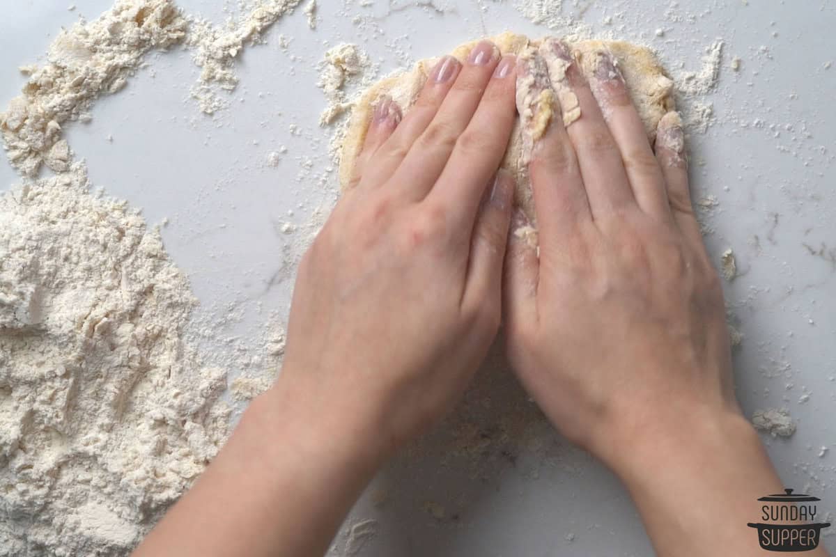 the dough being mixed with hands on a cutting board