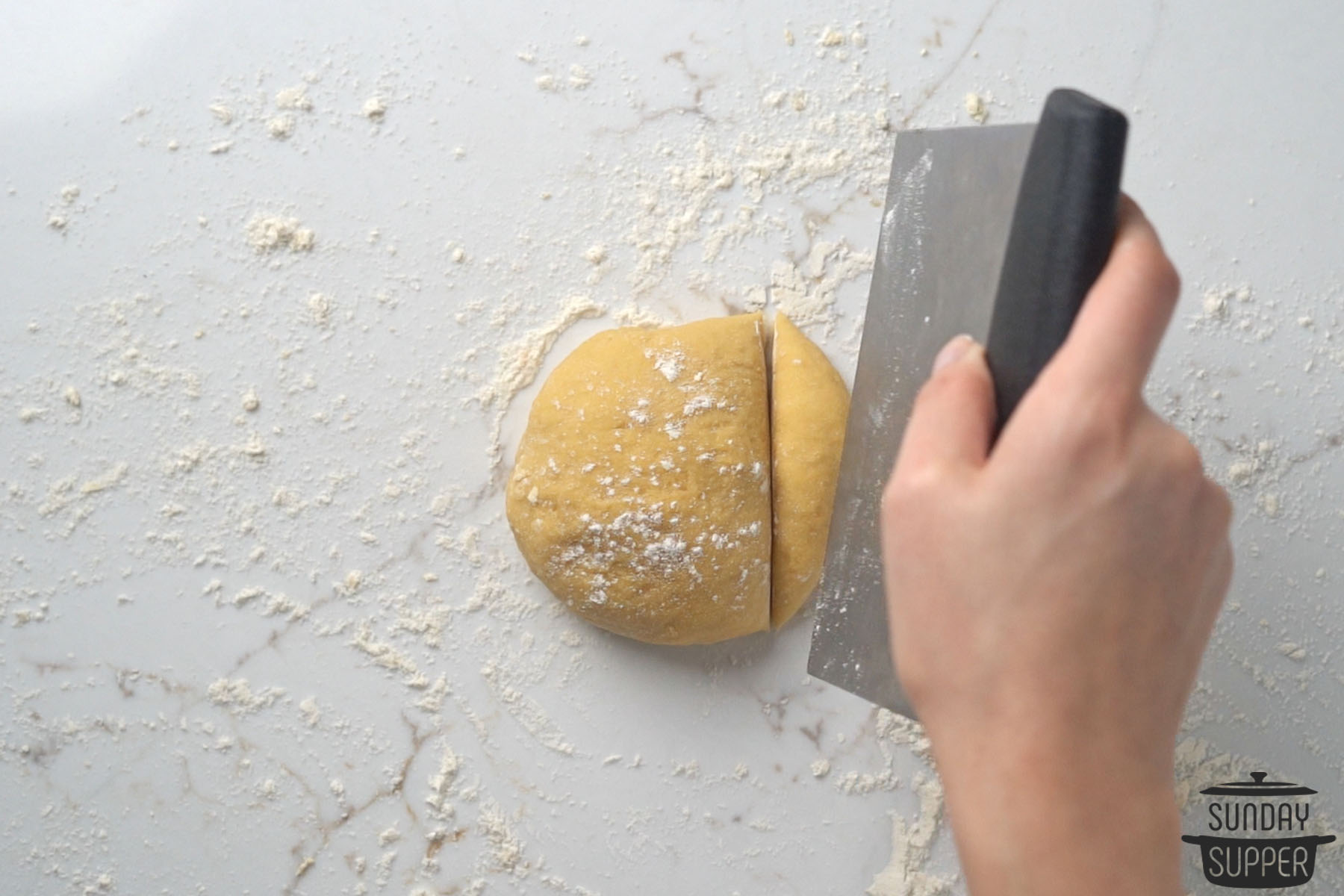 slicing off a portion of the dough with a pastry cutter