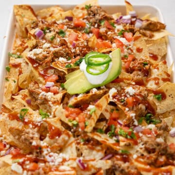 close up of pulled pork nachos on a white tray