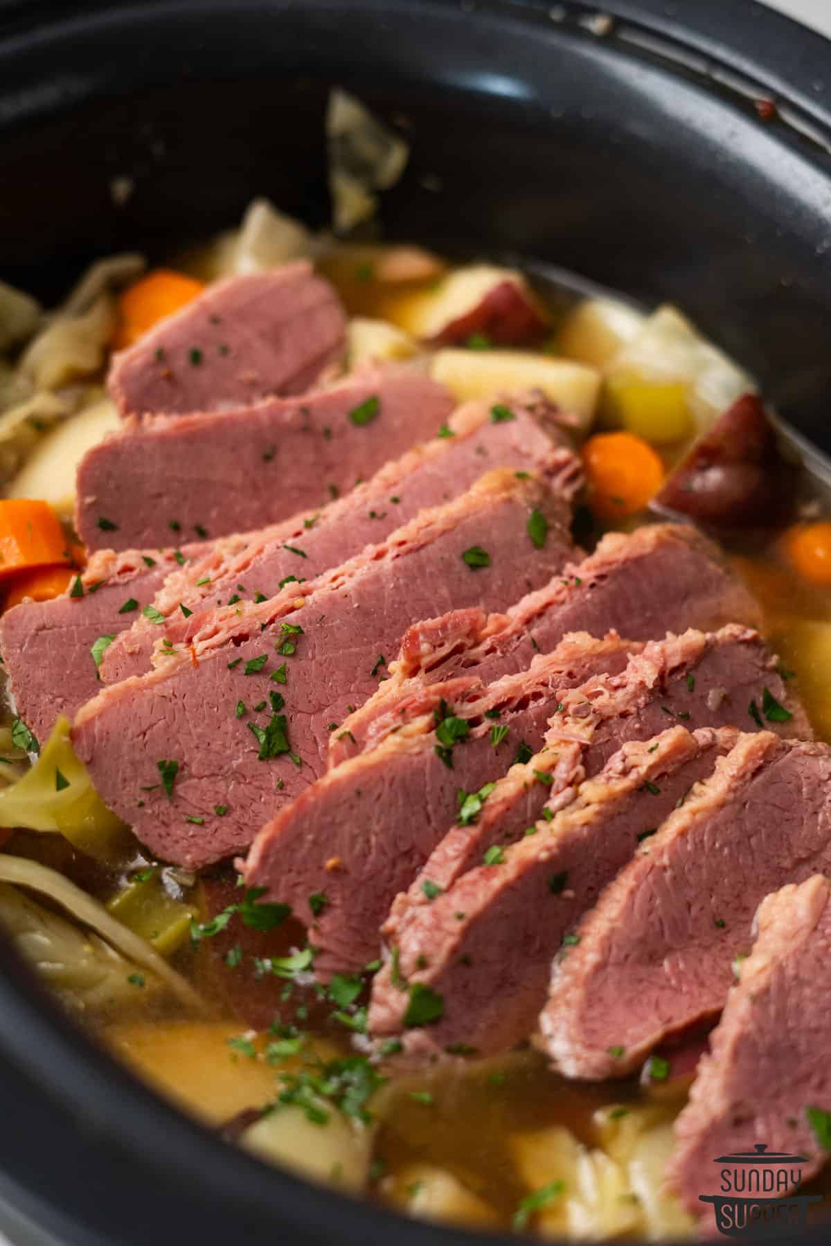 corned beef sliced in a slow cooker pot