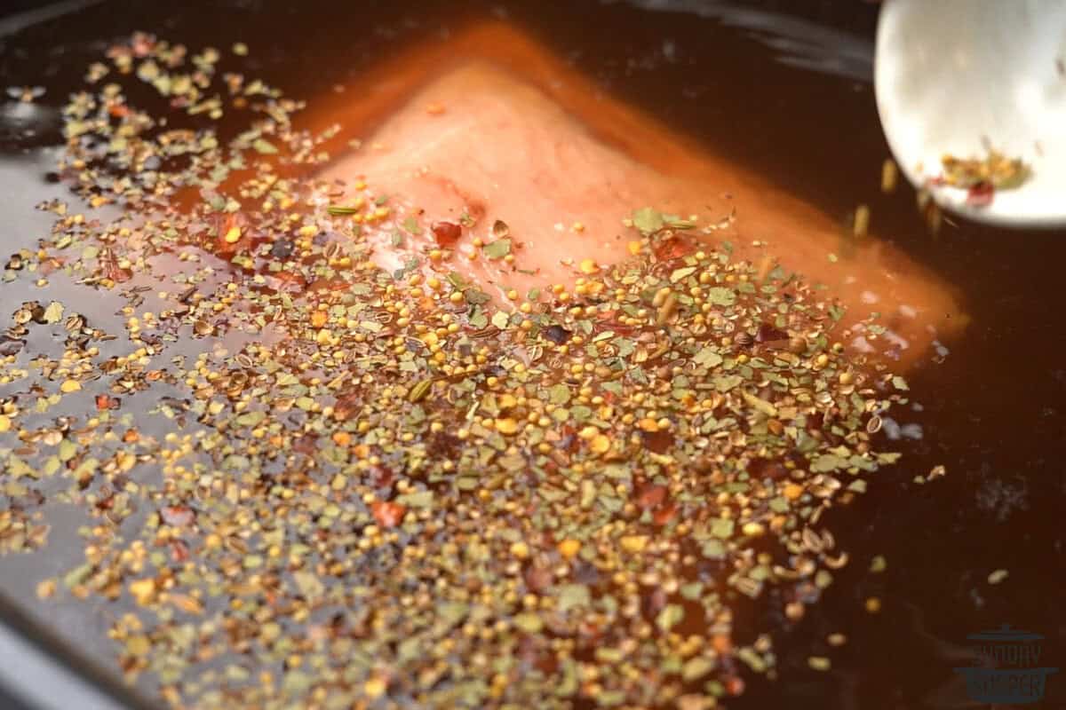 seasonings being added to the slow cooker