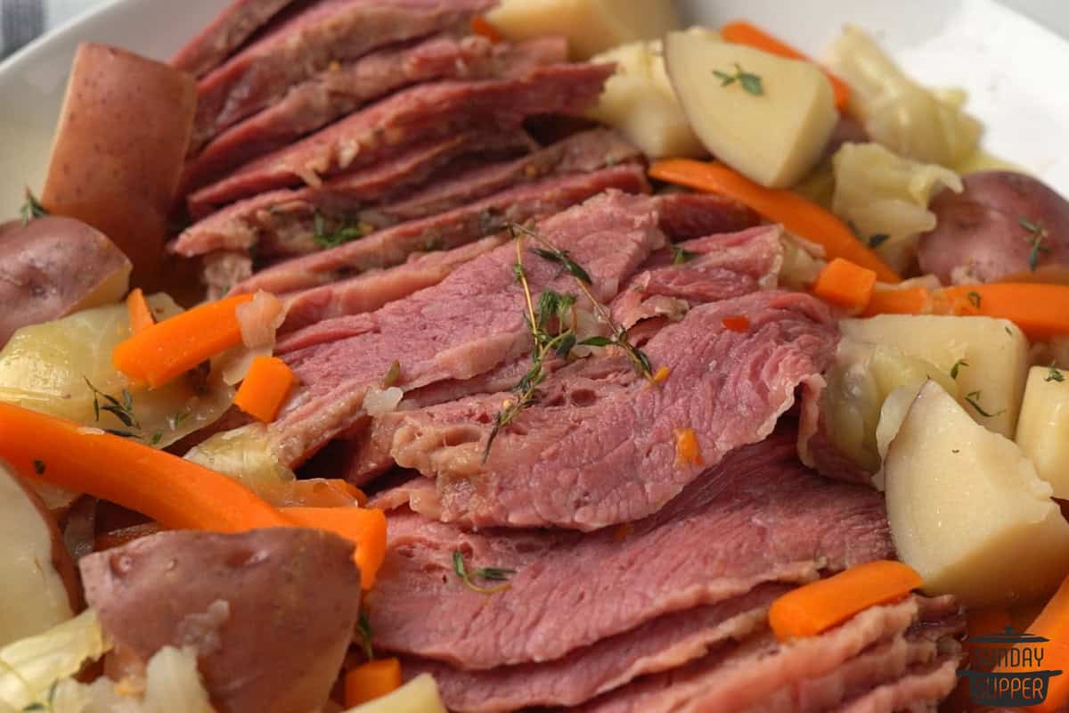 sliced and cooked corned beef with cooked vegetables on a plate