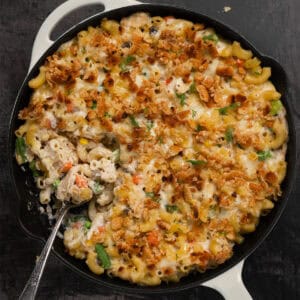 a spoon full of tuna noodle casserole in a pan